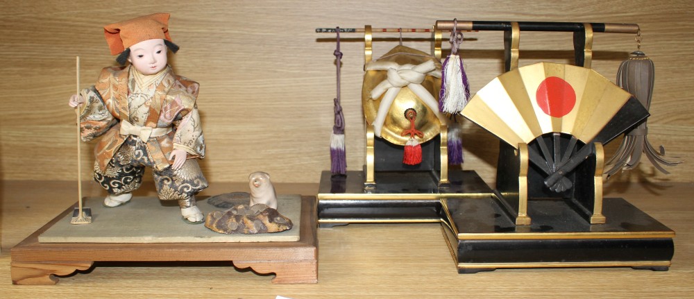 A Japanese late Meiji period composition and fabric figure of a boy farmer holding an adze with puppy seated nearby, mounted on display